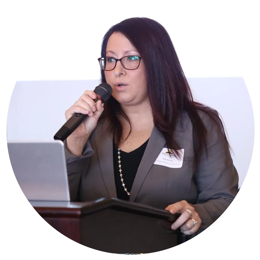Elika Maria speaking into a microphone at a lectern